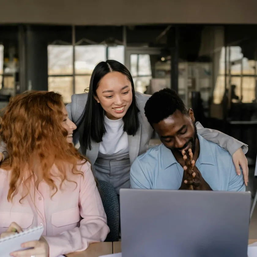 Two female and one male digital advertising buyers in front of a laptop screen