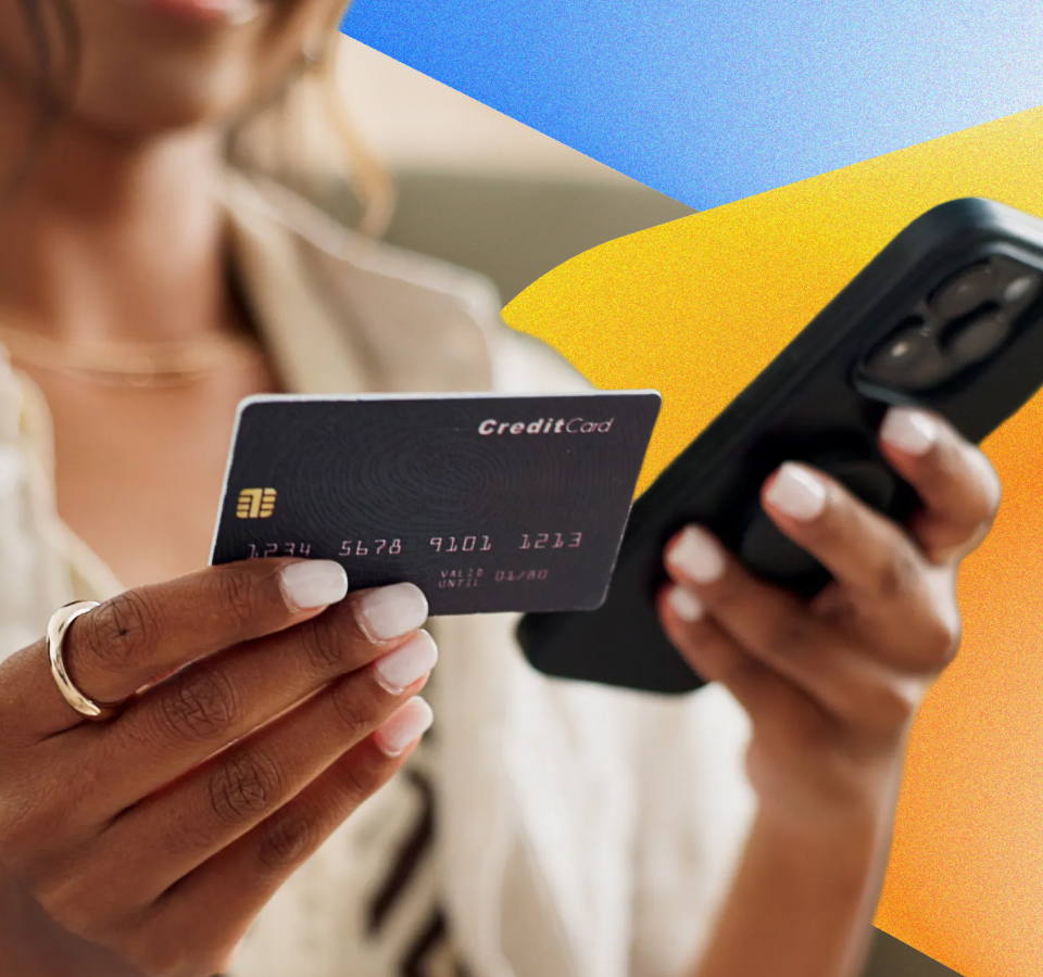 Person holding a credit card and smartphone while making an online purchase.