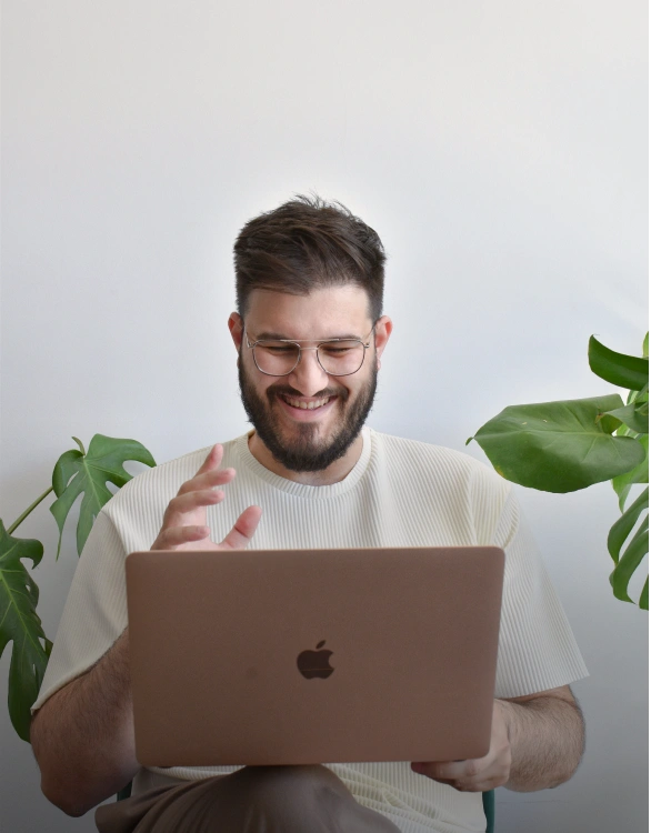 An individual facing a laptop that is open and appears to be engaged in conversation over a video call with his colleagues.
