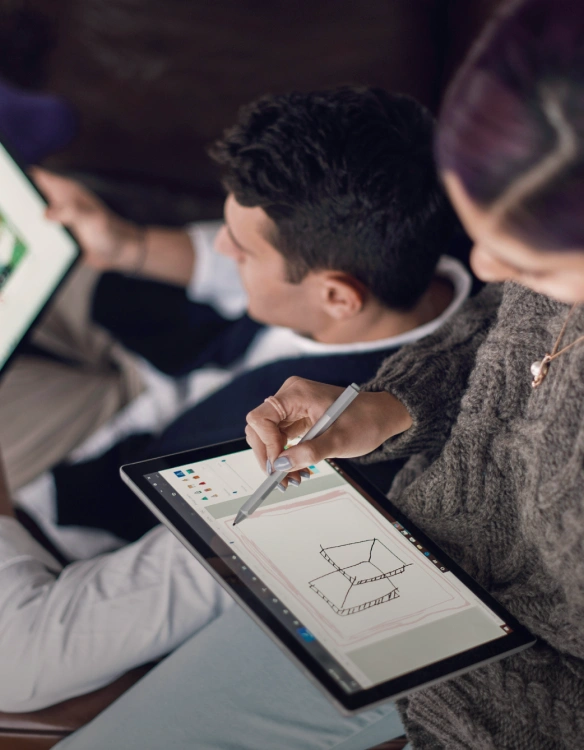 Two individuals are reviewing content on tablets, with one individual actively diagramming and/or sketching out a conceptual design with a stylus pen.