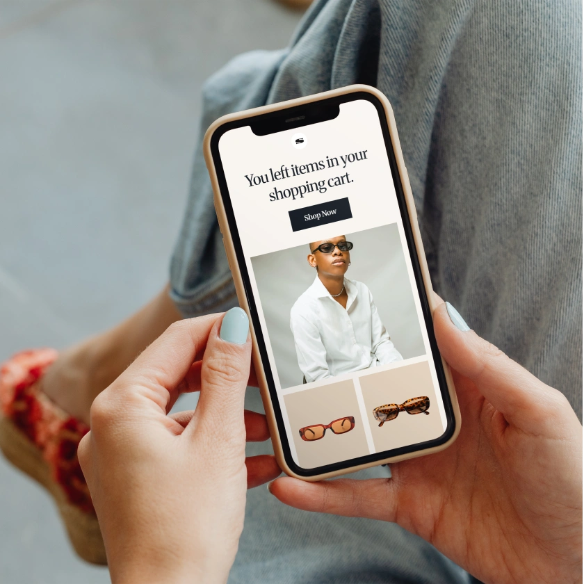 Close-up of hands holding a smartphone displaying an online shopping cart reminder.