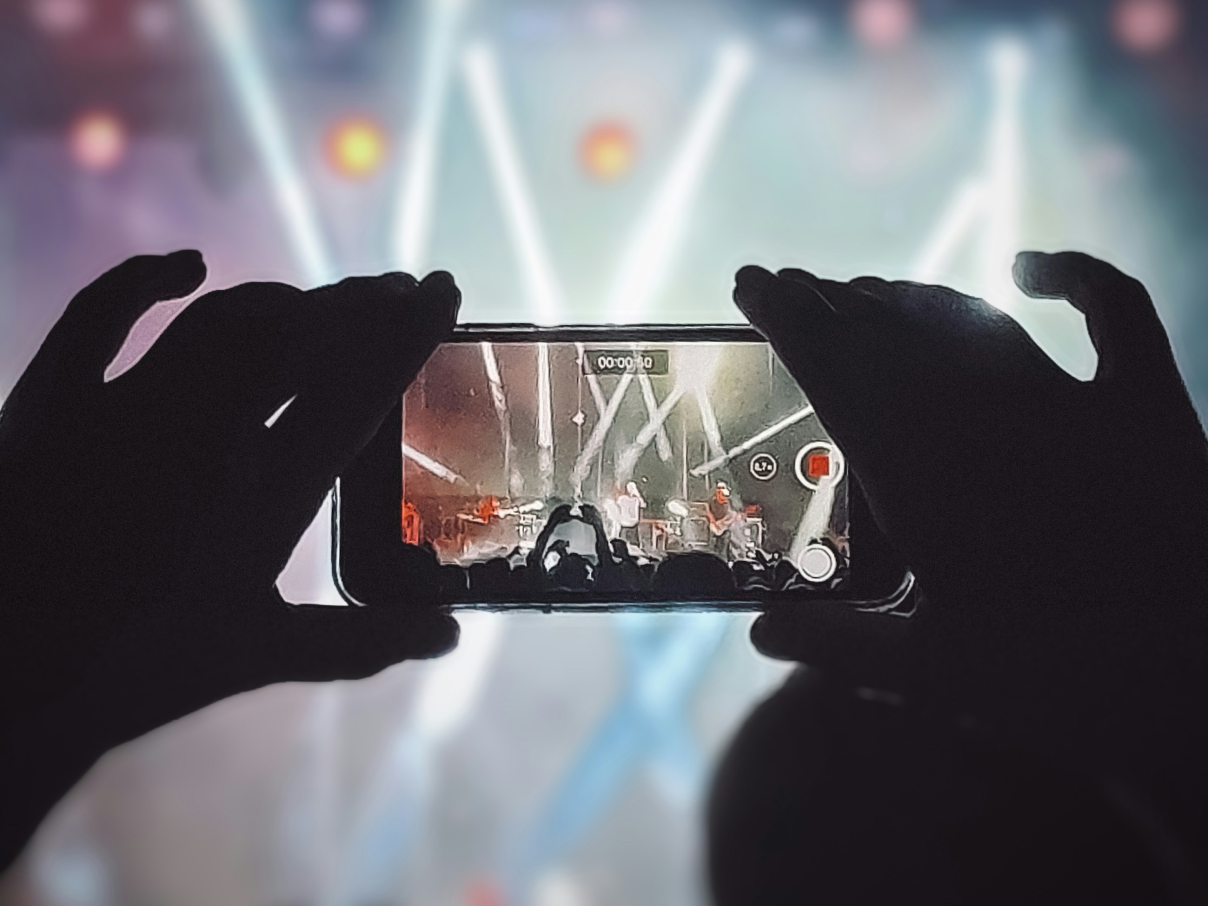 Concert goer recording show on mobile device.