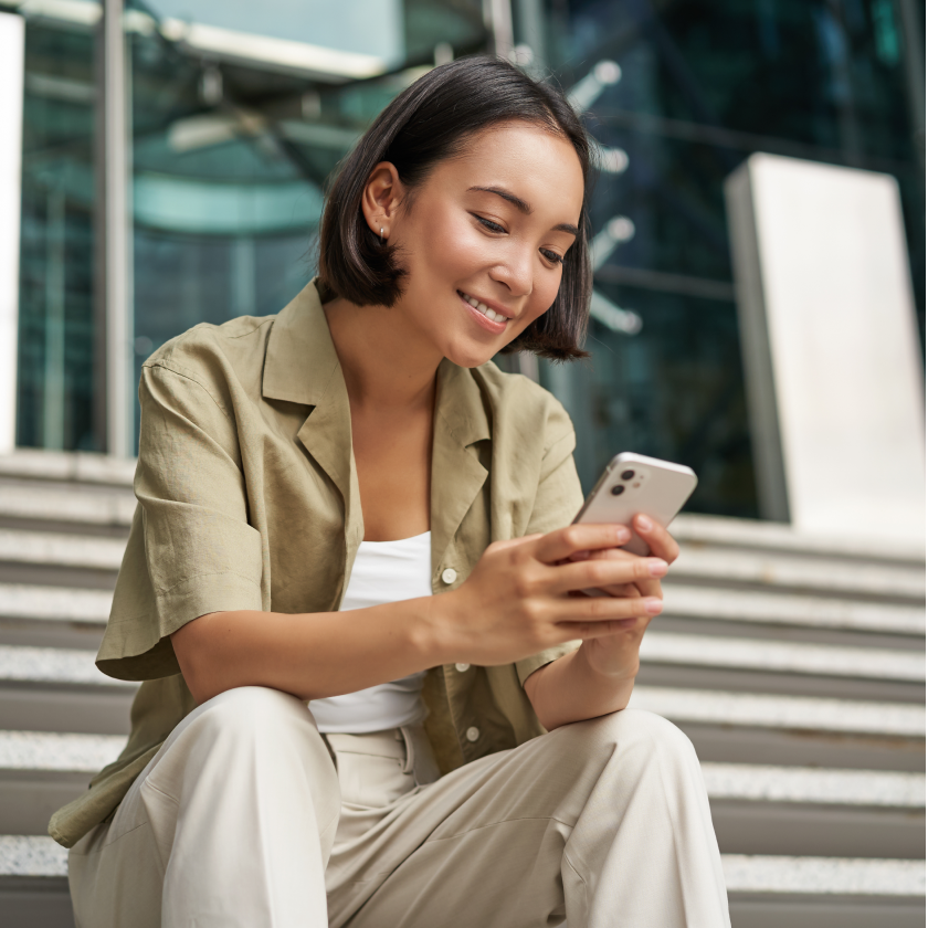 Person sitting on outdoor steps and using a smartphone.