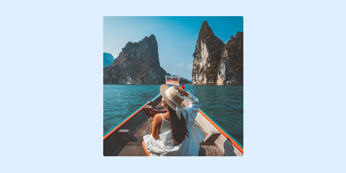 Traveller sitting on a boat looking out at coastal cliffs, representing leisure travel and destination experiences.