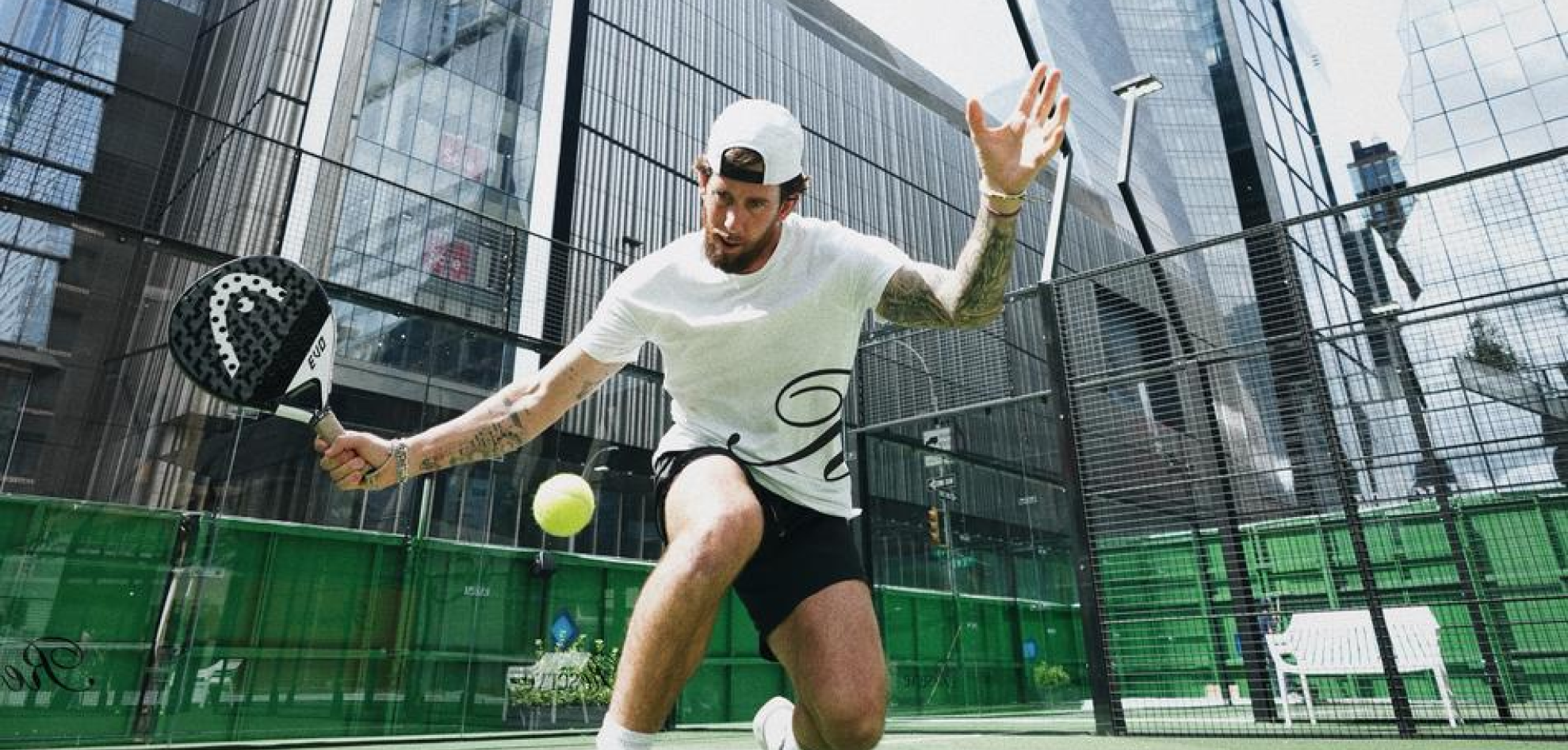 Person in mid-swing with a padel racket on a court.