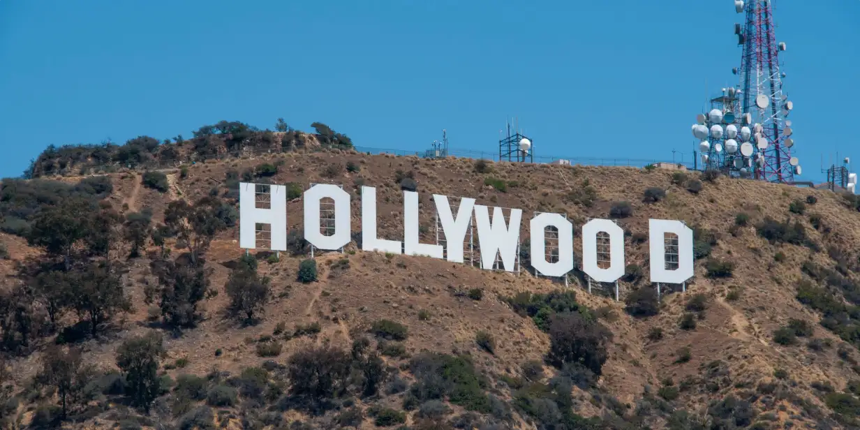 The iconic white Hollywood Sign situated on a dry, grassy hillside